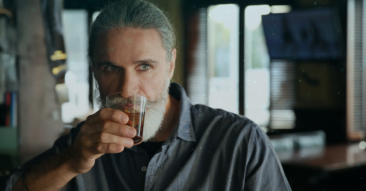 man with grey hair drinking a beer