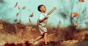 autumn leaves blowing in the wind with a boy playing