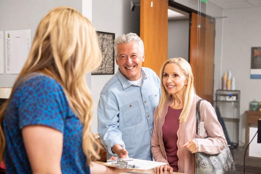 Couple checking in and smiling with a receptionist at Amen Clinics