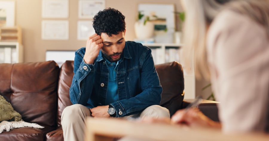 Man sitting on a couch looking distracted during a conversation