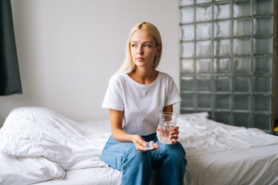 Woman sitting on a bed holding a glass of water