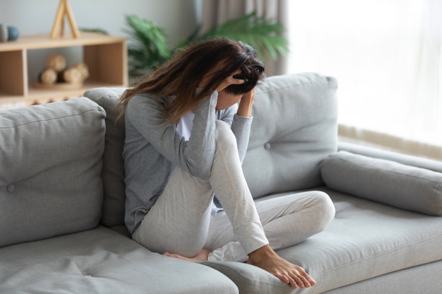 Woman sitting on a couch with her head in her hands