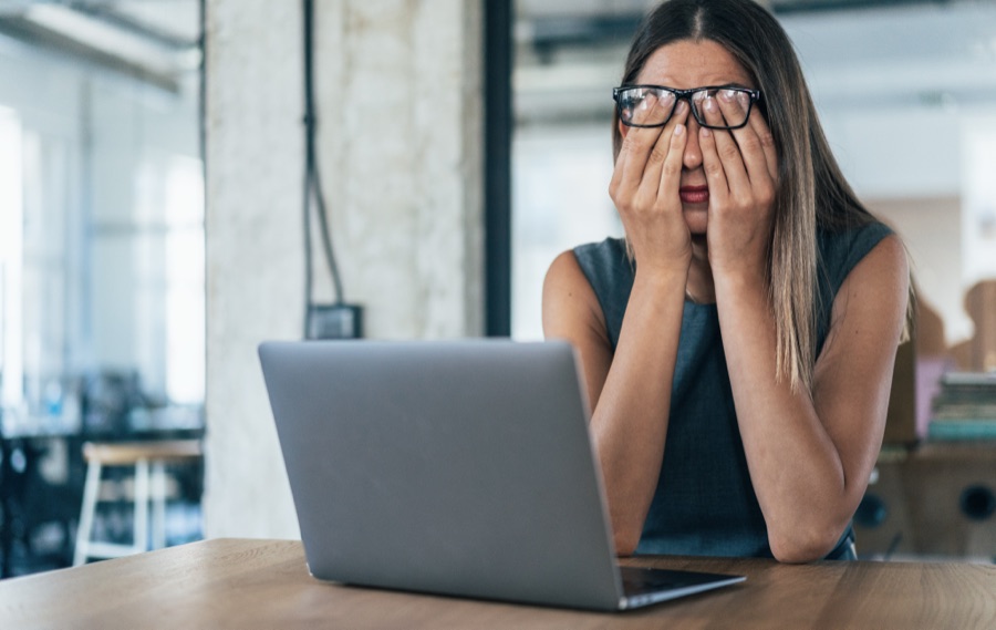Woman sitting at a laptop late at night looking exhausted