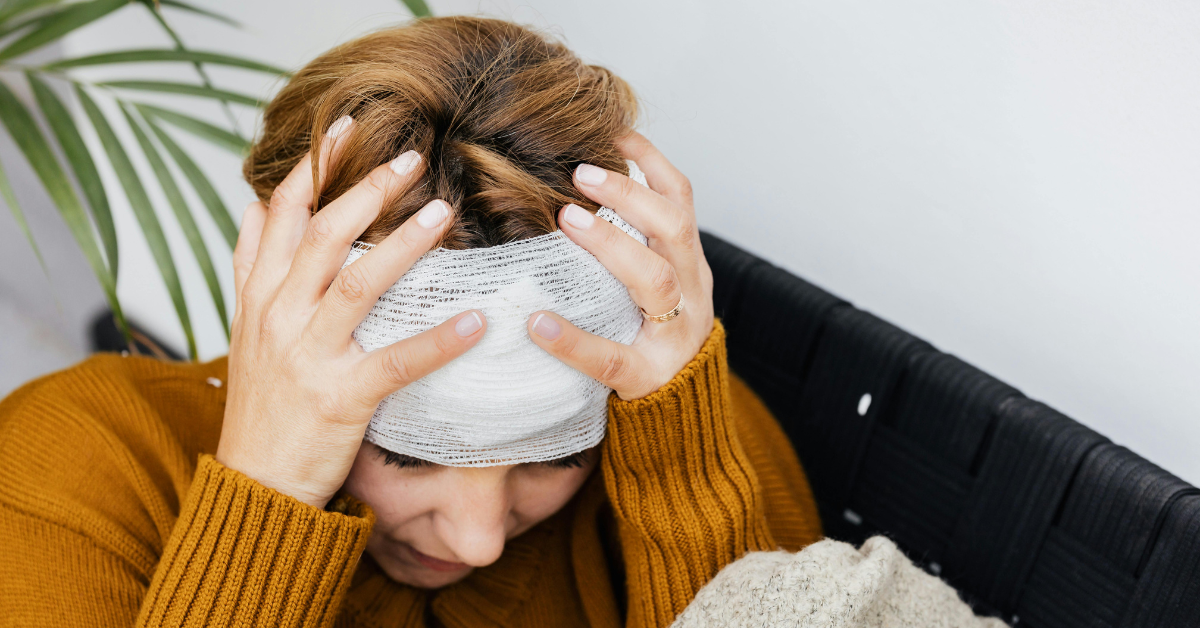 Person with a head bandage holding their head with both hands.