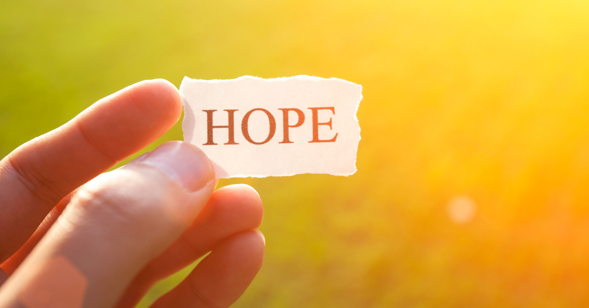 hand holding a paper that says hope in the sunlight