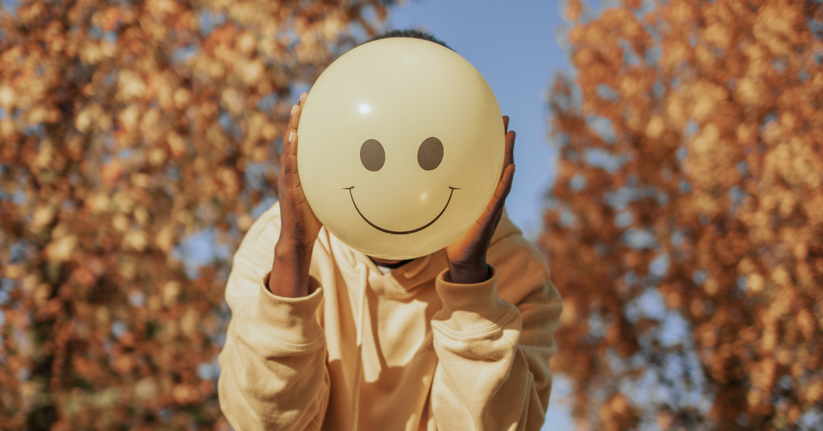 person holding a happy face balloon