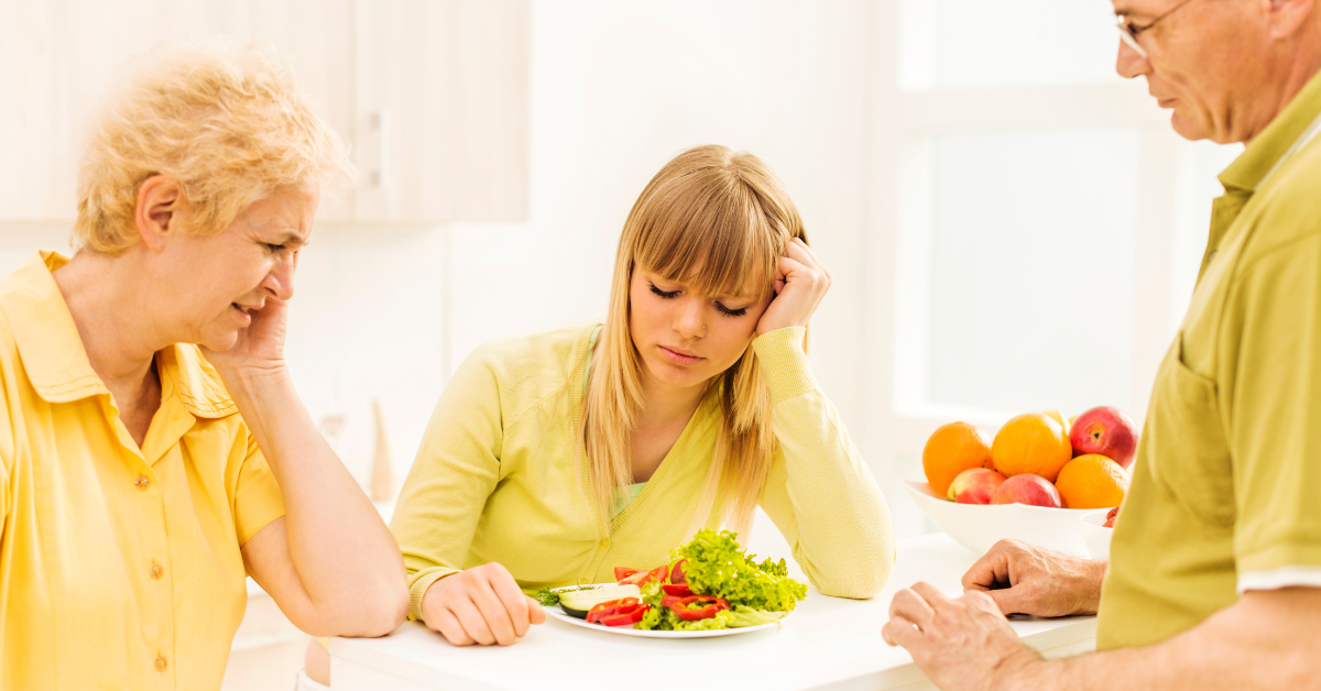 A man and woman sitting at a table with a plate of food