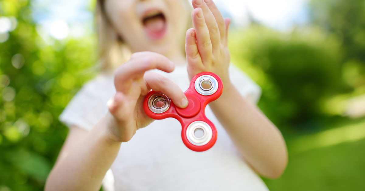 A child is playing with a red fidgetr